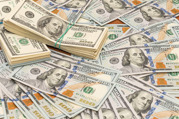 Many hundred dollar bills on wooden table background texture. bundles of money scattered on the office desk. wealth and income concept