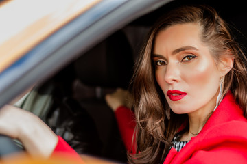 Fototapeta na wymiar brunette portrait in a long red coat near in orange car