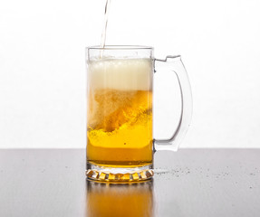 Beer is poured into a glass glass on a white background.