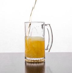 Beer is poured into a glass glass on a white background.