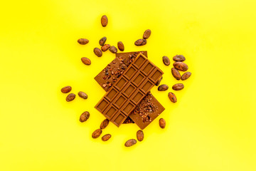 Chocolate - stack of dark bars - on yellow background top-down copy space