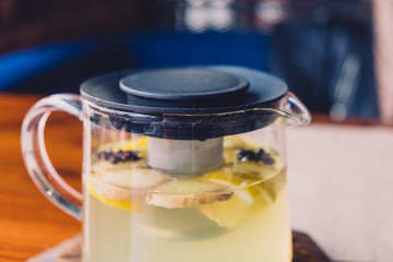 Transparent glass kettle stands on a table it is filled with herbal tea