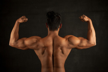 Tanned trainer body builder posing back biceps athletic body