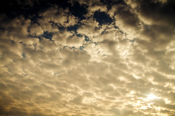 The sky is covered with small clouds. The sun shines through the clouds. Background. Autumn. Sunset. Evening.