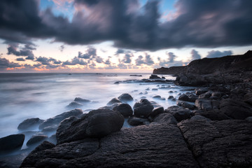 Obraz premium Amazing long exposure seascape with rocky beach at sunrise in the blue hour