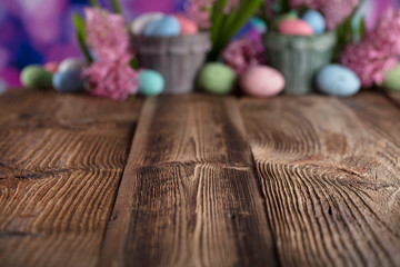 Easter background. Rustic wooden table. Tulips and spring flowers. Easter eggs. Pastel colors bokeh. 