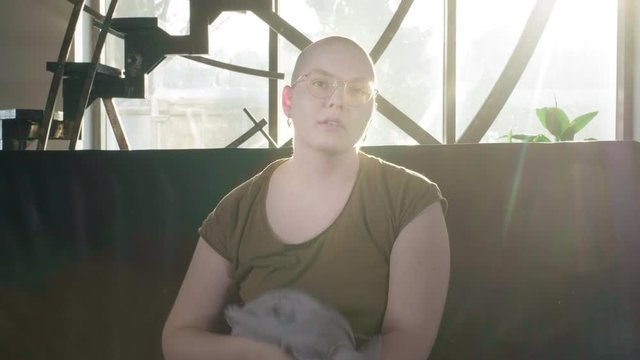 Portrait of pale woman sick with cancer, request for help, social protection. A bald girl with cancer or leukemia puts a scarf on her head. Tie fabric on head. She completed a course of chemotherapy.