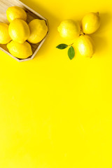 Ripe lemons in tray on yellow backgroud top-down frame copy space