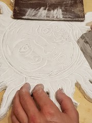 The sculptor processes the bas-relief of the sun
