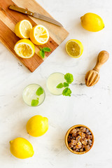Homemade lemonade in glasses near juicer and cut lemons on white background top-down