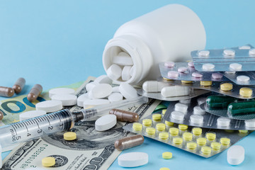 Medical pills are on a money on a blue background. Medical pills on money background as a symbol of...
