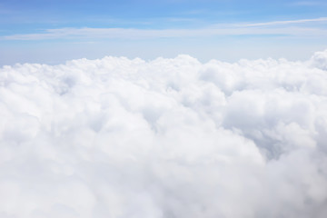 Aerial view of cloudscape from aircraft window show mass of soft white clouds and freshness tropical summer blue sky background before landing.