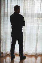 Silhouette photo of thinking man standing near tulle