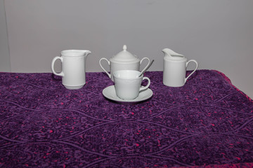 Juego de tea o café, sobre mesa con mantel morado y pintas rojas