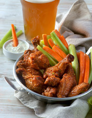 Buffalo chicken wings with vegetables and a glass of beer