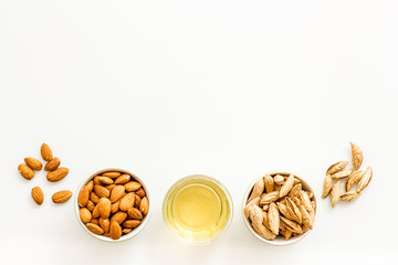 Almond oil - for cooking - in glass bowl near nuts on white background top-down copy space