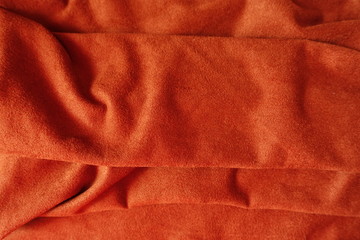 Folded bright reddish orange artificial suede fabric