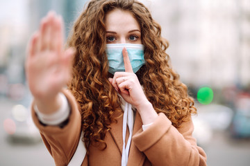Healthy woman in blue medical protective mask showing gesture stop. A hand, a Stop sign, a stop...