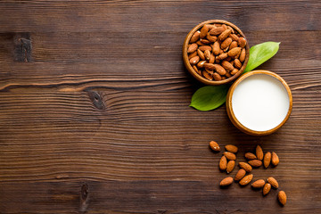 Almond milk near nuts on wooden background top-down copy space