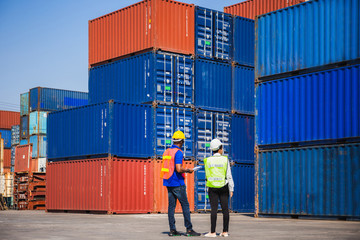 Female foreman with safety vest holding laptop and  worker man in hardhat checking and control...