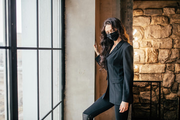 A woman in a medical mask looks out the window.