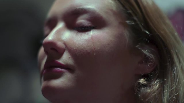 Slow motion shot of crying woman with a tear falling down her cheek