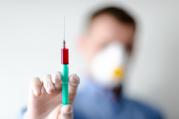 Pandemia COVID-19, lekarz w masce trzymający strzykawke na testy