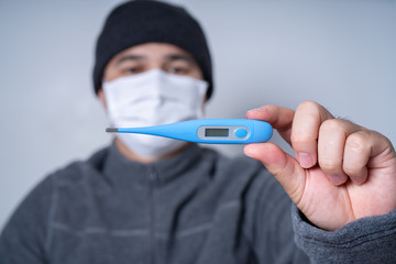 COVID 19 Pandemic Coronavirus protective spreading disease virus by checking with clinical thermometer ; Man wearing face white mask