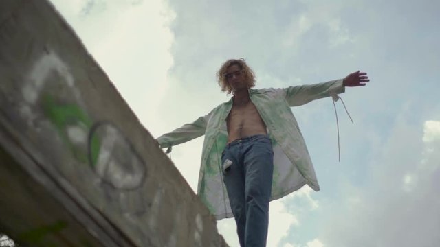 Slow motion shot of young blond man balancing on a wall