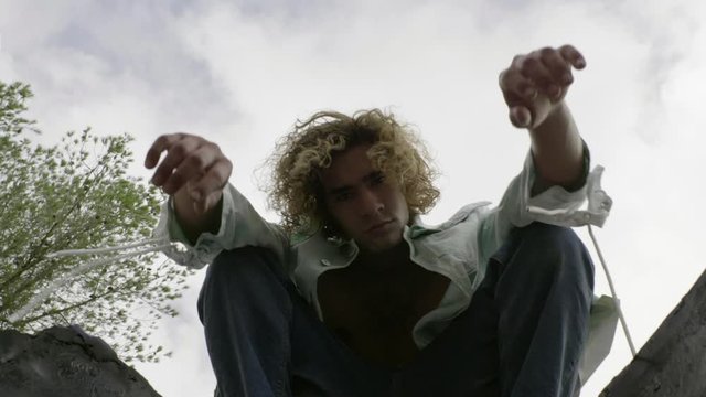 Slow motion shot of young blond man sitting on a wall