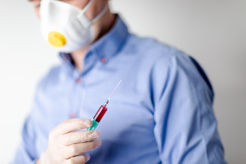 Pandemia COVID-19, lekarz w masce trzymający strzykawke na testy - obrazy, fototapety, plakaty