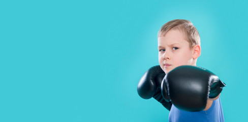 Portrait of cheerful boy with black boxing gloves on blue background