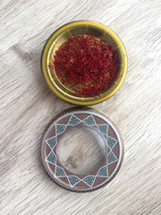 Dried saffron stigmas in beautiful box on wooden background. Iranian luxury saffron. Top view. Vertical image.