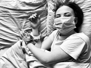 a teenage girl in a medical mask in bed during corona virus quarantine time lack of freedom