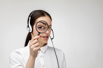 search concept. Beautiful woman consultant of call center in headphones holding magnifying glass on...