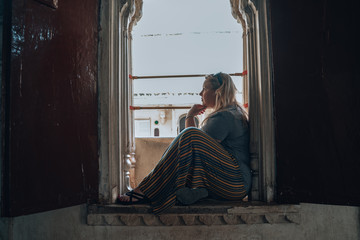 Pensive blonde woman sits in a windowsill, thinking. Taken in Udaipur India