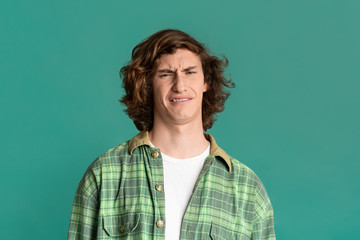 Millennial guy with disgusted expression on turquoise background
