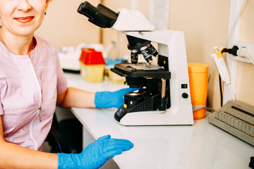 Blood test process in laboratory. Doctor looking through a microscope. Coronavirus blood testing.