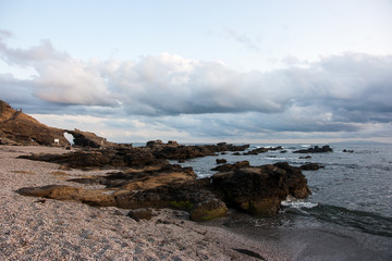 golden hour by the ocean with heavy clouds