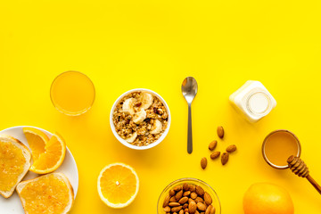 Morning granola near toast and oranges on yellow background top-down frame copy space