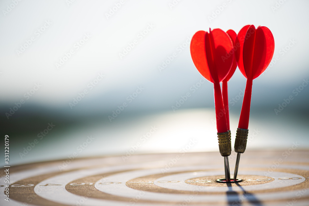 Wall mural close up shot red darts arrows in the target center on dark blue sky background. business target or 