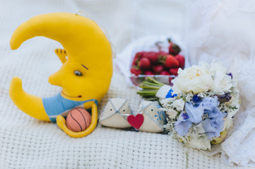 Wedding details for weddings and honeymooners: a bouquet of peonies and gladioli, a pillow with a heart, a soft toy a month with a basketball. Photography, concept.