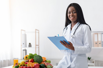 Positive black female dietologist holding medical chart