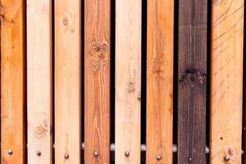 Rustic wooden fence made from treated differently colored boards. Vertical background wall made of vintage pine wood in vintage style.