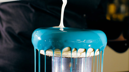 Close-up of a pouring a syrup glazing over cake. Professional confectionery.