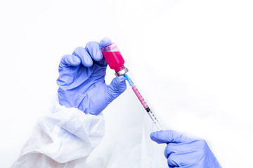 Hands of a virologist in a virus-proof suit and medical gloves fills a syringe with medicine. hands with a syringe on a white background.