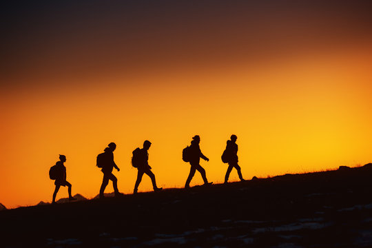Five hikers going uphill at sunset