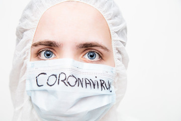 A virologist in a virus- proof suit and medical mask reflects on the consequences of the coronavirus epidemic. The doctor is thinking how to stop the virus. fear in the eyes