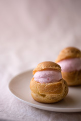 Obraz na płótnie Canvas Homemade choux cream or cream puffs with strawberry cream on pink background.
