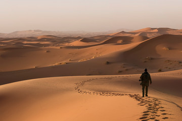 Man walking through the desert dunes